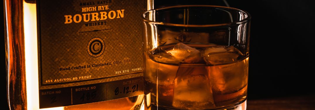 Close Up of a Rocks Glass of Bourbon and a Bottle of Small Batch High Rye Bourbon